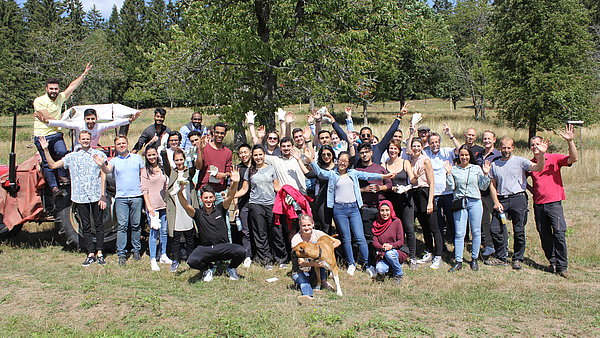 Eine große Gruppe junger Menschen auf der Streuobstwiese freut sich nach einem Arbeitseinsatz
