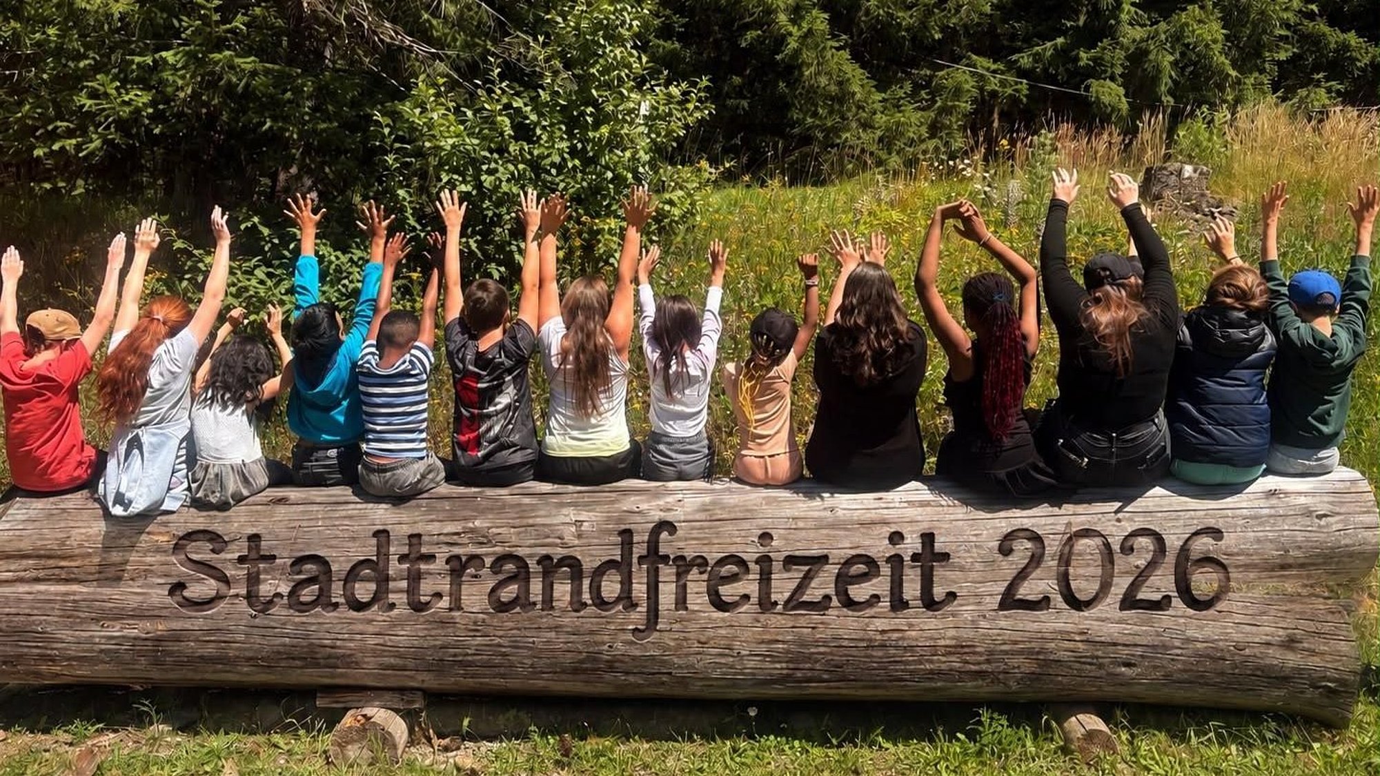 Kinder sitzen auf einem Baumstamm am Waldrand