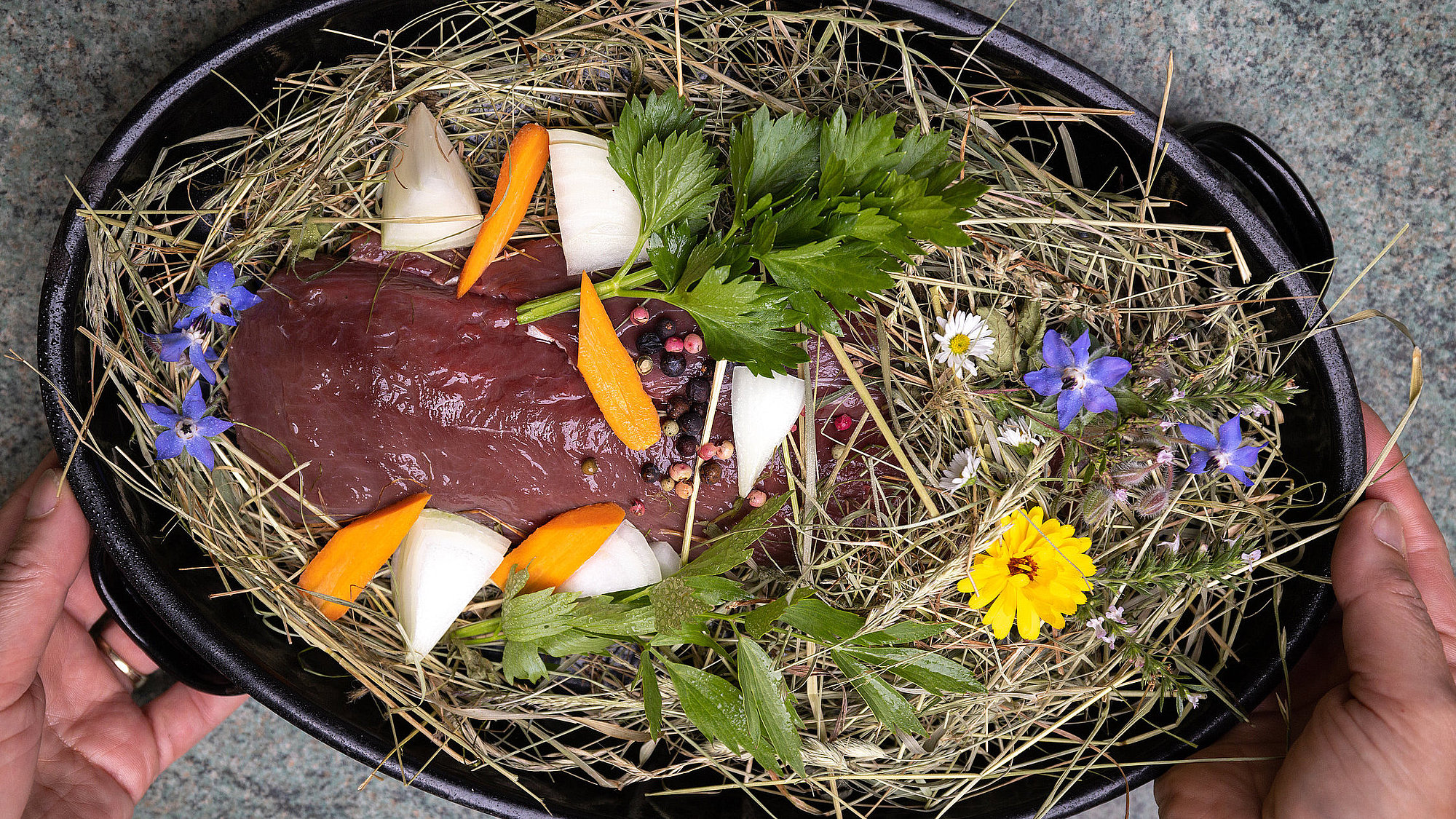 Wildfleisch auf Heubett mit Wildkräutern