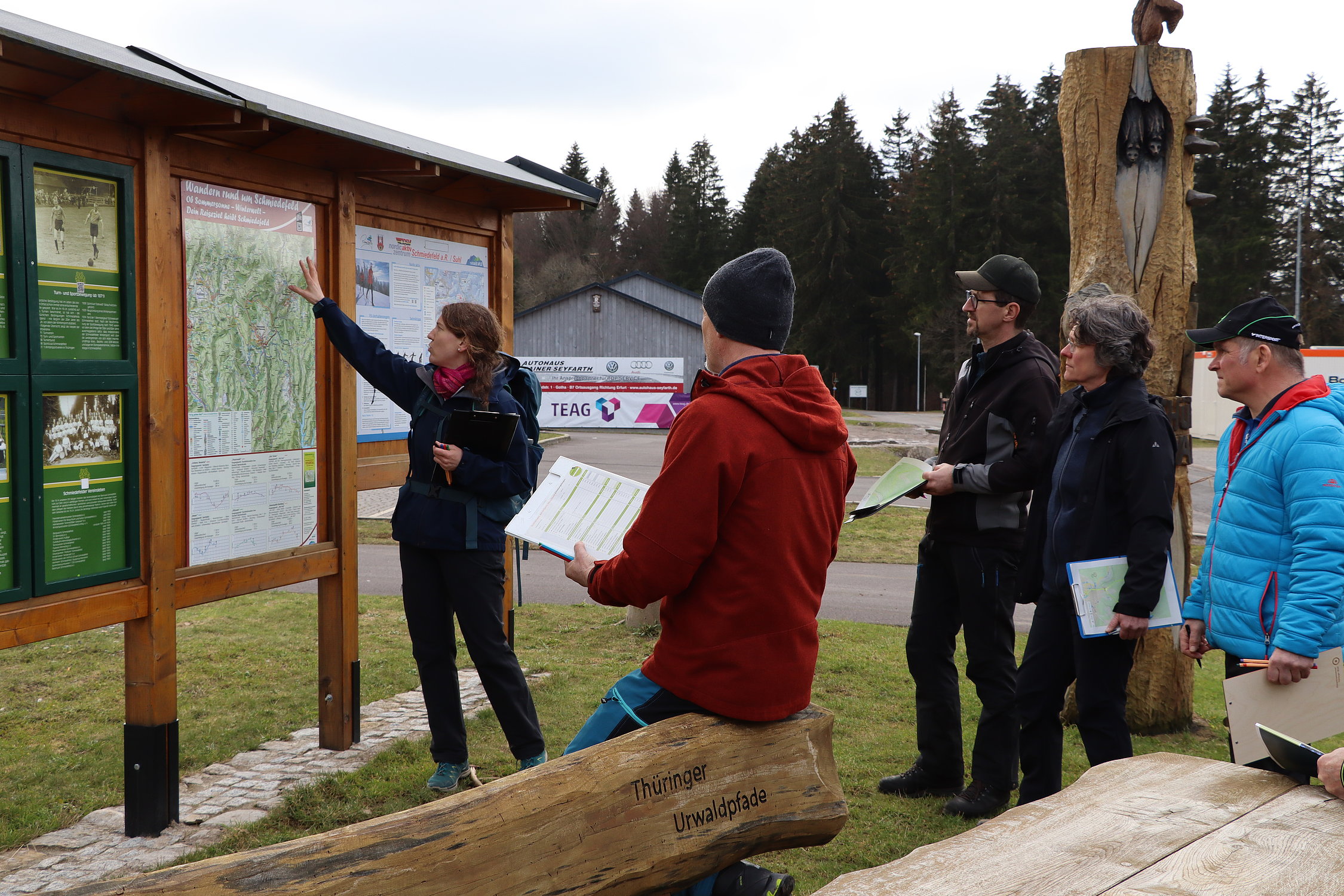 Frau an Wanderkarte mit Wandergruppe
