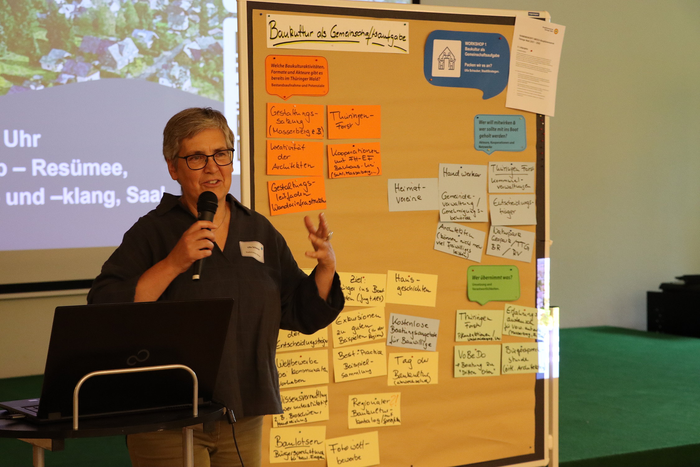 Frau vor Pinnwand erklärt Ergebinsse aus Workshop